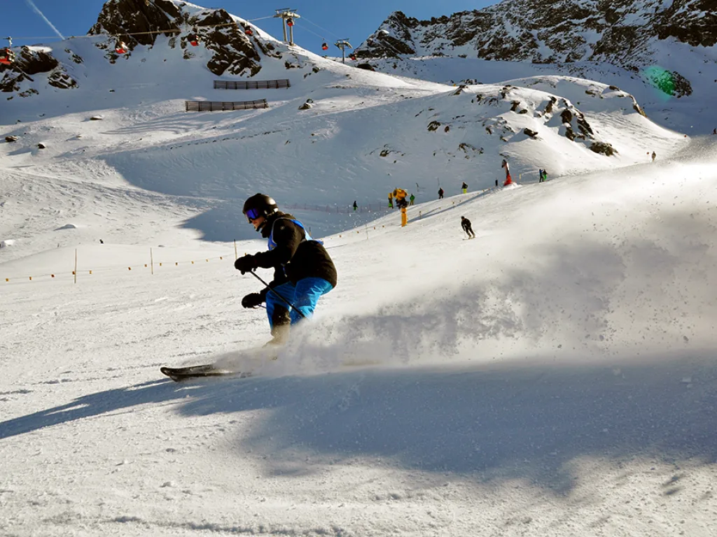 Snowboarder fährt mit aufstiebendem Schnee talwärts.